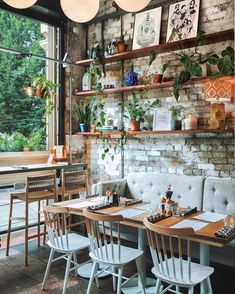 the interior of a restaurant with tables, chairs and plants on the wall above them