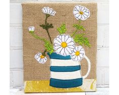 a painting of flowers in a blue and white striped vase on burlap background