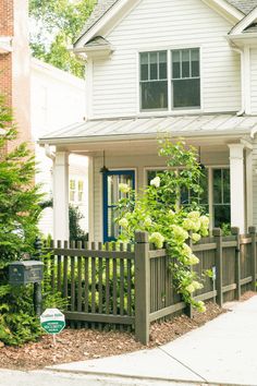 a white house with a blue door and fence