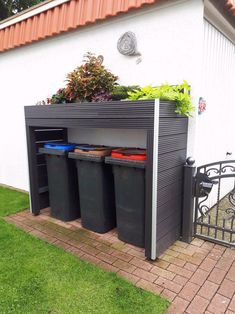 an outdoor storage area with trash cans and plants