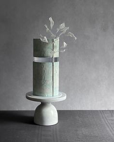 a three tiered cake sitting on top of a white stand with flowers in it