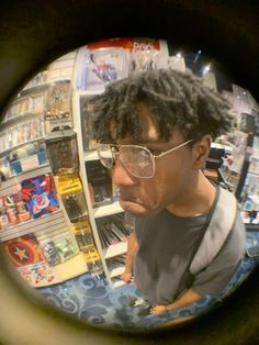 a man with glasses is looking through a magnifying glass at the store's shelves