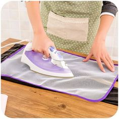 a woman ironing fabric on top of an ironing board with a purple and white electric iron