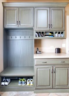 a kitchen with gray cabinets and shoes on the counter top, in front of an open door