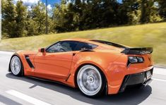 an orange sports car driving down the road