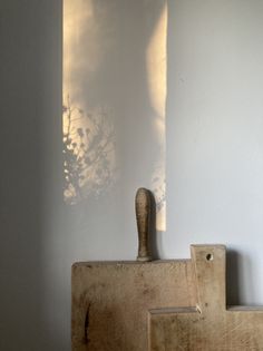 a wooden block with a handle on it in front of a white wall and shadows