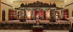 an elaborate stage set up for a wedding ceremony with flowers on the floor and decorations