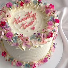 a white cake with pink and blue flowers around it that says twenty five on top