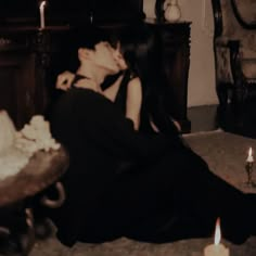 a woman sitting on the floor next to a cake with candles in front of her