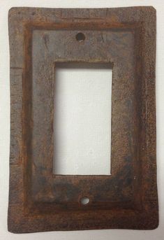 an old rusted metal square frame on a white wall with a hole in the middle