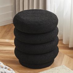 a stack of black towels sitting on top of a wooden floor next to a window