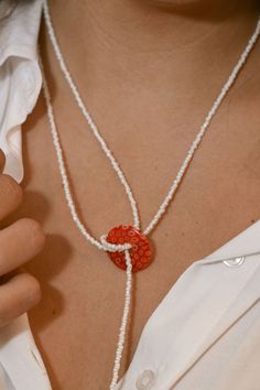 a close up of a person wearing a necklace with beads and a heart on it