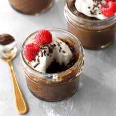 three desserts in small jars with raspberries on top and chocolate pudding below