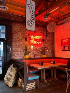 the inside of a restaurant with neon signs and tables in front of brick walls,