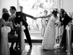 the bride and groom are holding hands as they walk down the aisle