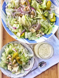 two plates filled with salad and dressing on top of a wooden table next to each other