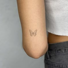 a woman's arm with a small butterfly tattoo on the left side of her arm