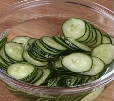 sliced cucumbers in a glass bowl on a wooden table