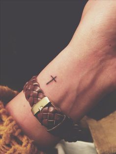 a person with a cross tattoo on their wrist