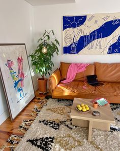 a living room filled with furniture and a painting hanging on the wall above a coffee table