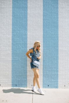 a woman standing in front of a blue and white wall with her hands on her hips