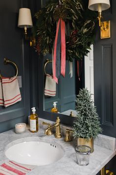 a bathroom sink with a christmas wreath hanging above it