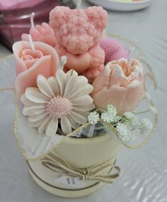 there are flowers and candles in the bowl on the table with other items around it