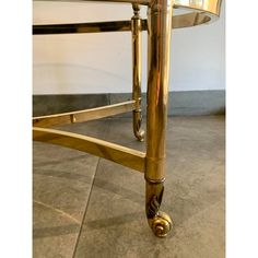 a gold metal and glass coffee table with wheels on the bottom, in an empty room