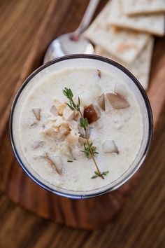 a close up of a bowl of food with crackers on the side and a spoon