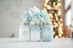 three mason jars with snowflakes and flowers in them