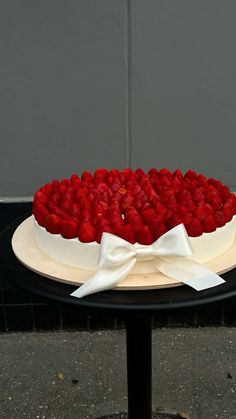 there is a cake with strawberries on the top and white bow around it's edges