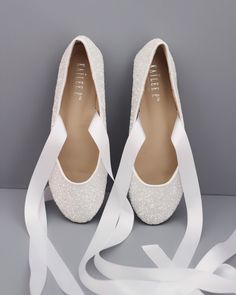 a pair of white wedding shoes with ribbons