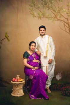 a man and woman pose for a photo in front of a tree with fruit on it