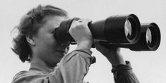 a woman looking through binoculars at the sky