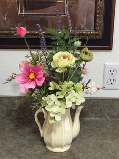 a vase filled with flowers sitting on top of a counter next to a light switch