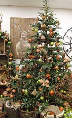 a decorated christmas tree in a living room with other holiday decorations and deer head on the wall