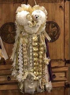 a teddy bear hanging from the side of a wooden door decorated with feathers and ribbons