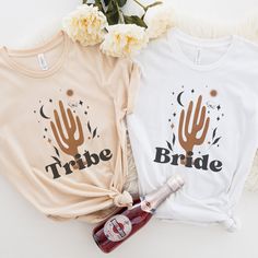 two t - shirts with the words tribe on them next to a bottle of booze