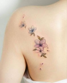 the back of a woman's shoulder with pink flowers on her left side and purple petals on her right arm