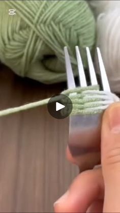 a person holding a fork with yarn on it