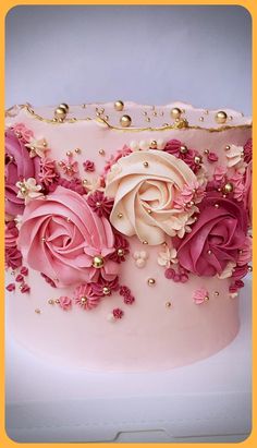 a close up of a cake with pink flowers on the frosting and gold decorations