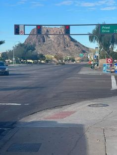 an intersection with two red traffic lights and a mountain in the backgrouund