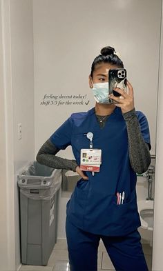 a woman in scrubs is taking a selfie with her cell phone and wearing a face mask