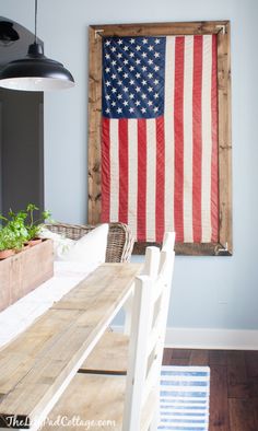 an american flag hanging on the wall above a dining room table with chairs and potted plants