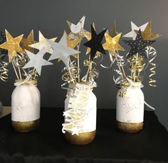 three mason jars filled with gold and silver stars on top of a black cloth covered table