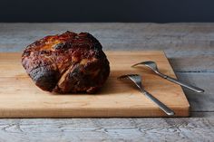 a piece of meat sitting on top of a cutting board next to a knife and fork