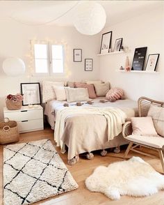 a small bedroom with white walls and wooden flooring is decorated in neutral colors, including pink