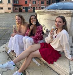 three women sitting on a bench eating ice cream