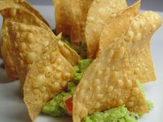 some tortilla chips with guacamole and tomato on top are sitting on a white plate