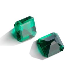 two emerald colored stones sitting next to each other